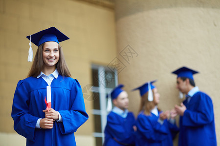 穿着毕业礼服的友好学生与前面的图片