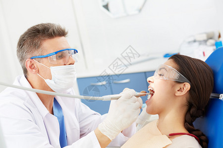 男牙医在牙科诊所治疗年轻女图片