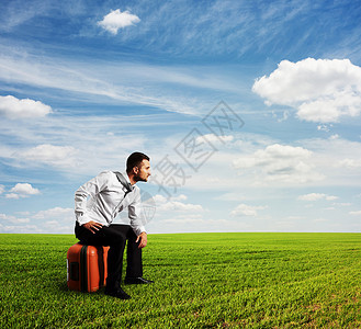 疲惫的男人坐在他的包上望着远方图片
