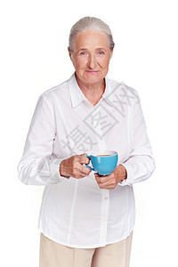 端着茶杯看相机的老年女肖像图片