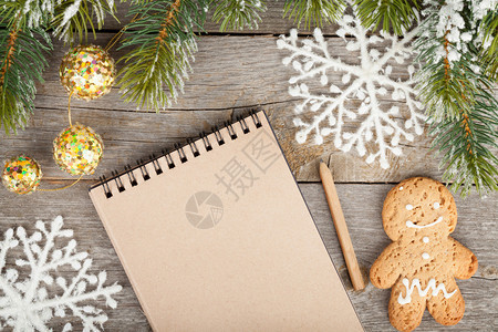 满雪装饰品和木板背景上空白笔记纸的图片
