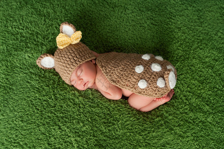 一名新生的女婴穿着白尾鹿牛装睡在青绿图片