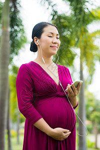 孕妇在外肚子里听古典音乐的垂直图像背景图片