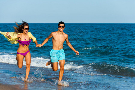 充满活力的青少年夫妇在海边奔跑和泼水图片