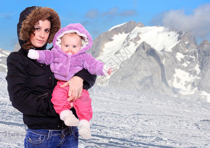 年轻高地人带着孩子穿着雪山的皮草季图片