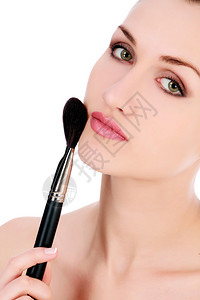 美丽的女人用化妆刷子在脸上化妆背景图片