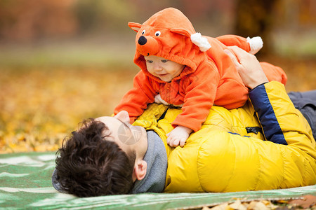 年轻父亲和他的小儿子穿着狐狸服装在秋天图片