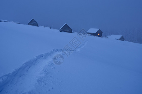 夜间冬季景观与雪中通往山谷小屋的路径山上的童话房子乌克兰图片