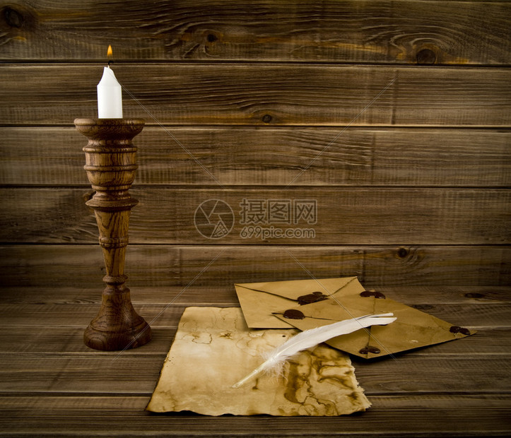 木制背景上的羽毛旧纸和蜡烛图片