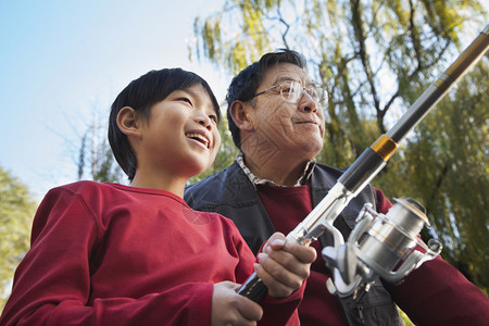 祖父和孙子在湖边钓鱼的肖像图片