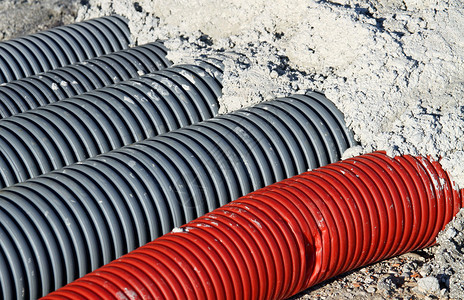 在混凝土覆盖的公路工程中铺设电缆和光纤的红色pvc冲压软管和背景图片