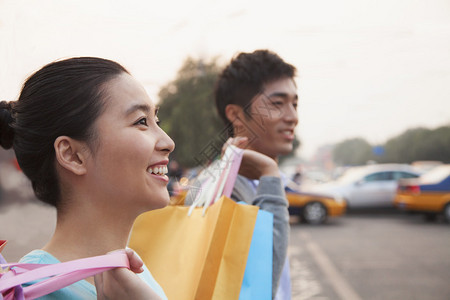 一对年轻夫妇在北京街上拿着购物图片