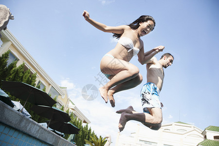 两个朋友牵着手跳进水池半空中图片