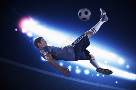足球运动员在空中空踢足球晚上以背景图片