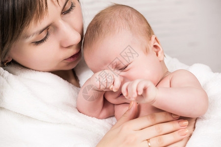 喜悦的年轻母亲与可爱的新生婴儿在家中玩乐照顾孩子幸福父母爱的概图片