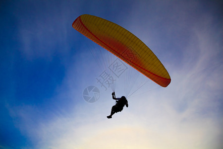 蓝天背光景上的滑翔伞剪影图片