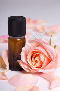 灰色背景下精油和玫瑰花瓣的特写图片