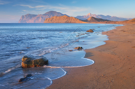 与沙滩的海景海上阳光明媚的早晨与岩石和海角的海岸图片