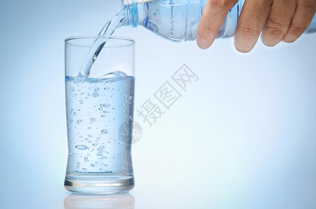 纯净的水从瓶子中倒入一杯图片