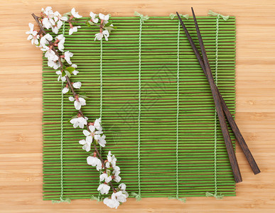 竹席上的筷子和樱花枝在白色背景下被隔离图片