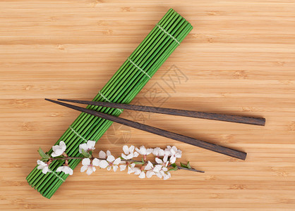 竹桌上垫子上的筷子和樱花枝图片