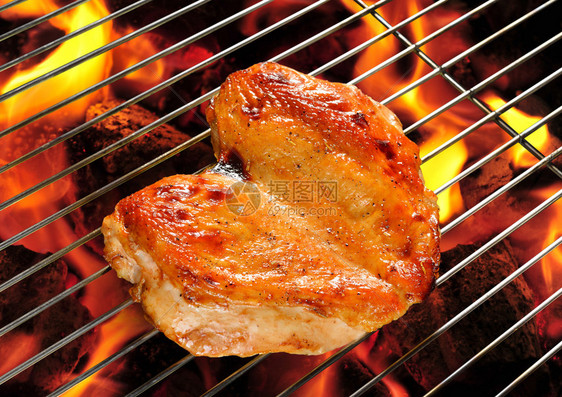 在燃烧的烤架上烤鸡胸肉图片