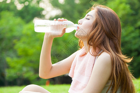 女人在运动后坐着疲惫的饮用水图片