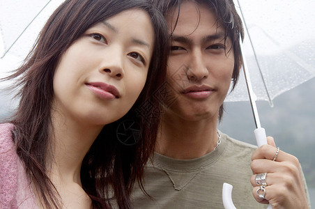 一对年轻的亚洲日本夫妇在雨天参观自然山景并拿着雨伞保护他们免受雨图片