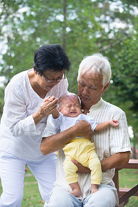 在户外抚慰哭泣的孙子婴儿图片