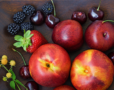 熟李子和桃子油桃甜樱桃黑莓红草莓和未成熟覆盆子的特写静物图片