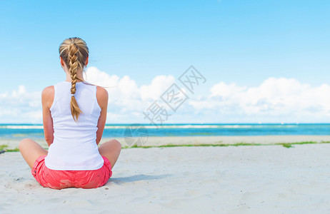 辫子女孩坐在沙滩上打坐图片