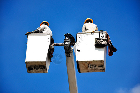 蓝色天空背景的桶里电气公用事业工人图片