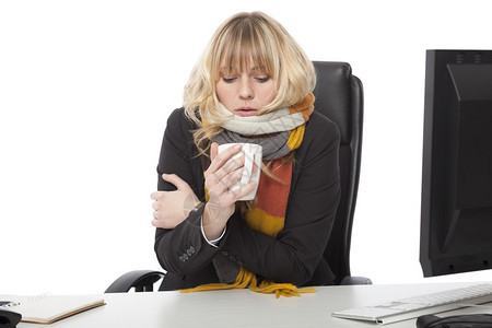 冷酷的女商人喝着一杯热咖啡当她坐在桌边坐着穿针织的图片