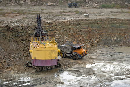 挖掘机在沙坑中装载自卸车图片