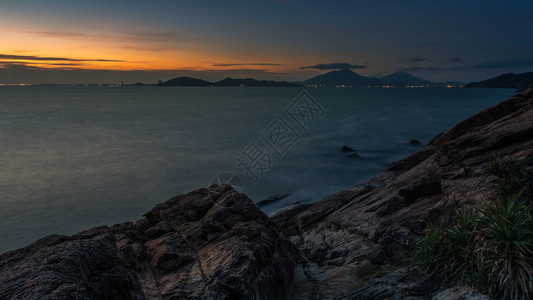 日落海景和浅地有草的岩石图片