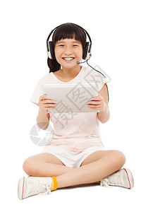 坐着的小女孩拿着带耳机的平板电脑孤立图片