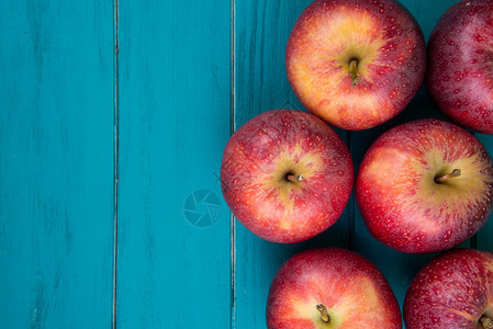 木制复古蓝色桌子上的新鲜有机红秋季苹果背景图片