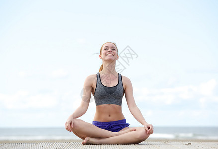 一位坐在瑜伽姿势和户外微笑的年图片