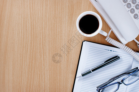 带笔记本钢笔和老花镜的客户服务人员木桌上背景图片
