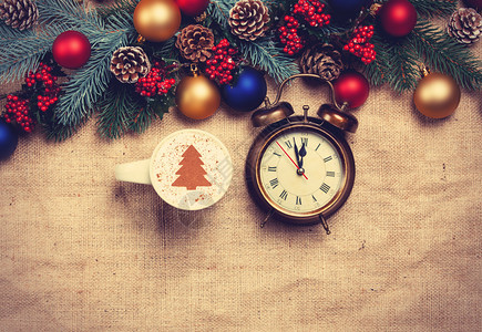 在松树枝附近的桌子上挂有圣诞树形状和闹钟的图片