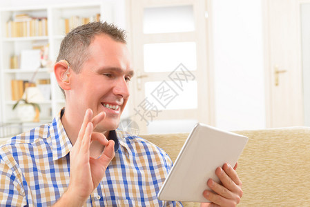 微笑的聋人使用手语在平板电脑图片