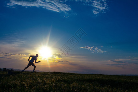 在草地上奔跑日出日落的天空在背景之下赛马手图片