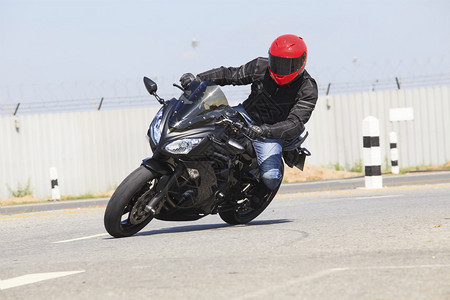 身穿安全西装和红色防敲头盔的青年男子骑着大型自行车摩托车图片
