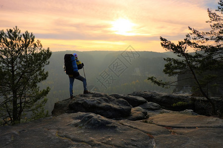 背着大背包的游客站在岩石的观点上图片