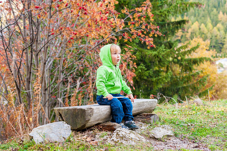可爱的小孩男在森林里休息穿着牛仔裤图片