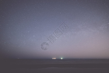 夜晚的灯塔夏季海滩上有星的夜空从地球看空间追溯背景