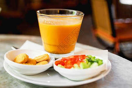 日本南瓜橙汤放在桌上的碗里配沙拉和面包图片