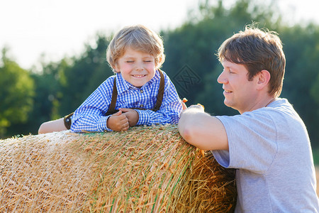 年幼的父亲和他的小儿子夏天在黄草田上玩得开心图片
