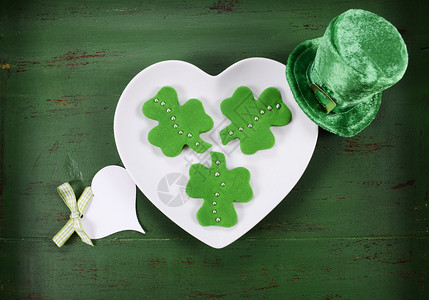 圣帕特里克节快乐在古老风格的绿色木桌上的白色心形板上塑造了图片