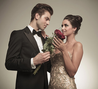 丈夫向他美丽的妻子献上一束红玫瑰他们互相看着对方呢图片